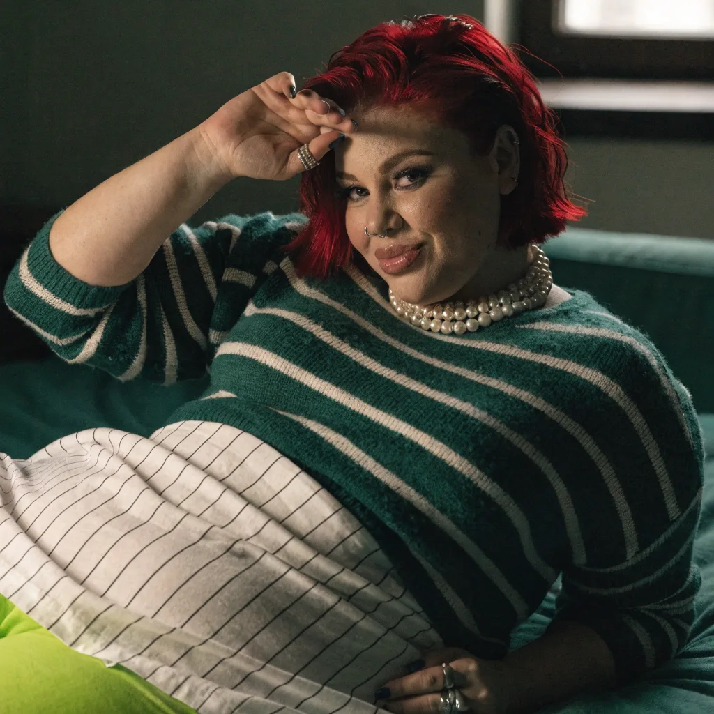 red-haired woman in a green striped sweater lounging